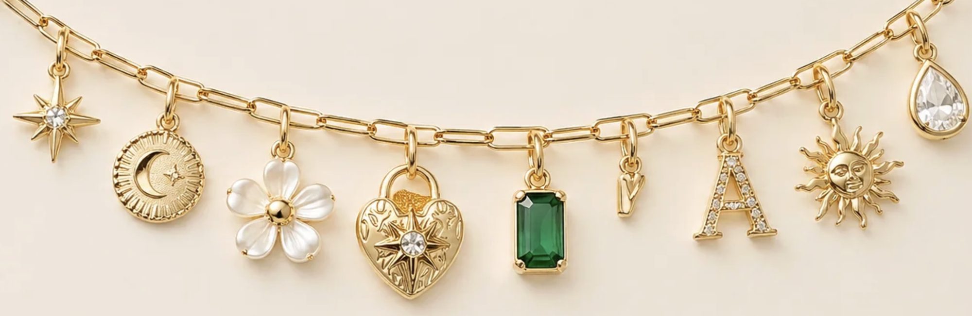Gold charm bracelet with star, moon, flower, heart, gem, letter, and sun charms