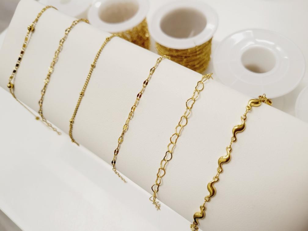 Stack of gold filled chain bracelets on a display table at a jewelry store.